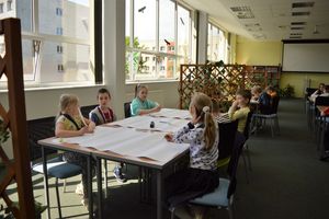 Dzieci siedzą przy stołach w czytelni Biblioteki Głównej