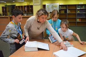 Bibliotekarka prezentuje trojgu dzieciom książki ze zbiorów Wypożyczalni Biblioteki Głównej