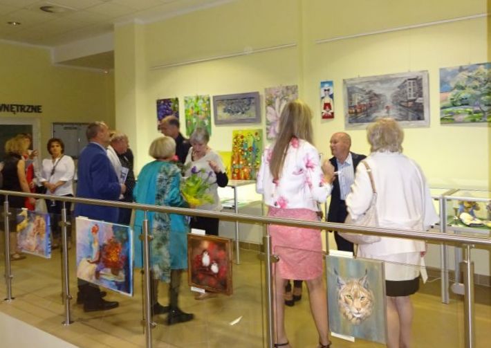 Grupa gości wernisażu oglądająca obrazy prezentowane na wystawie