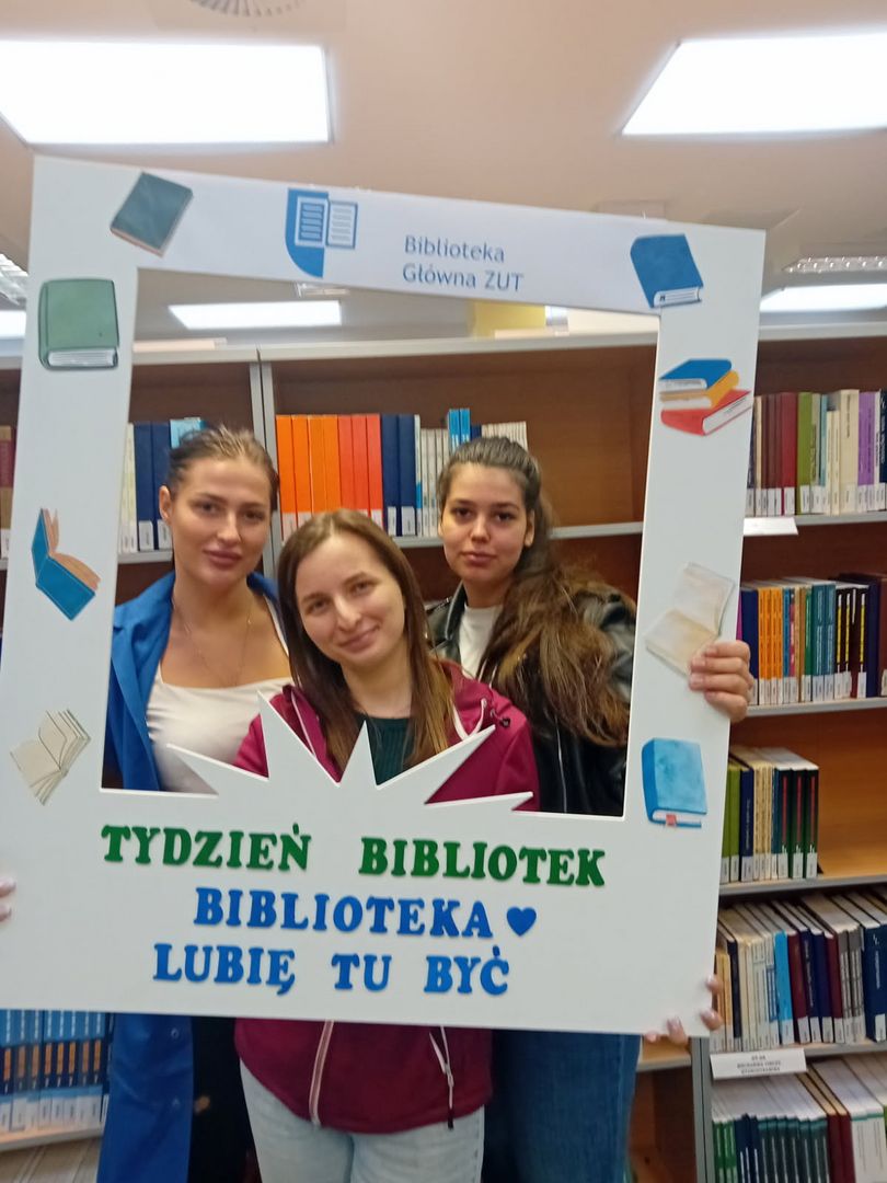 Trzy studentki w Wypożyczalni sfotografowane w okolicznościowej ramce Tygodnia Bibliotek