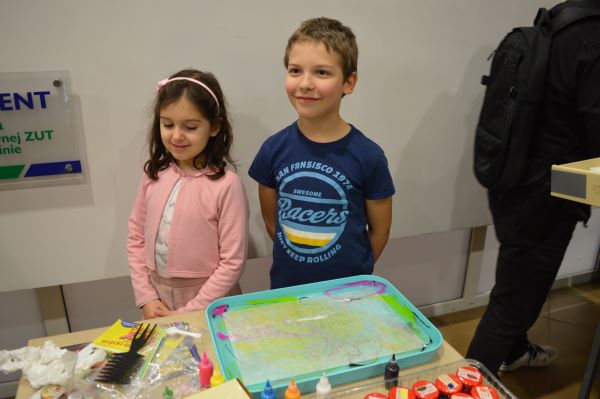 Dziewczynka i chłopiec za stołem z kuwetą i farbami