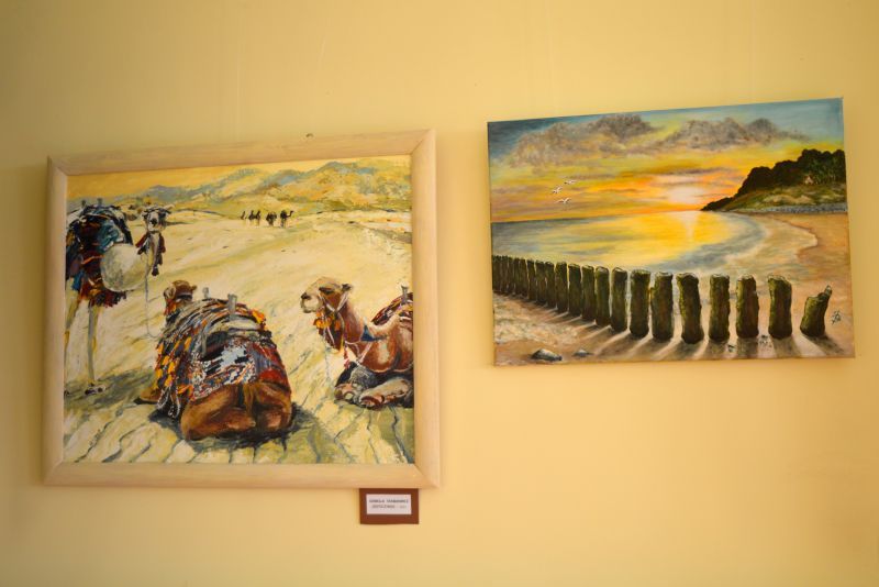 Dwa obrazy: jeden przedstawiający pustynny pejzaż z trzema wielbłądami, drugi pejzaż nadmorski o zachodzie słońca