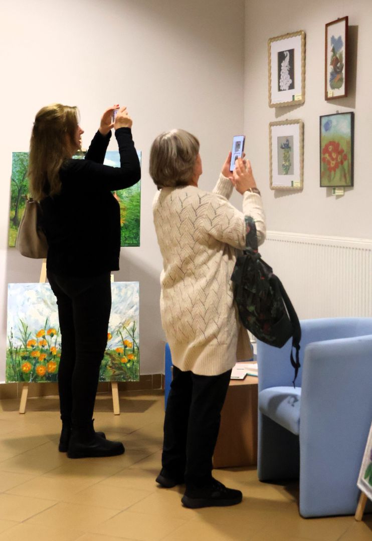 Dwie gościnie wernisażu fotografują obrazy prezentowane na wystawie