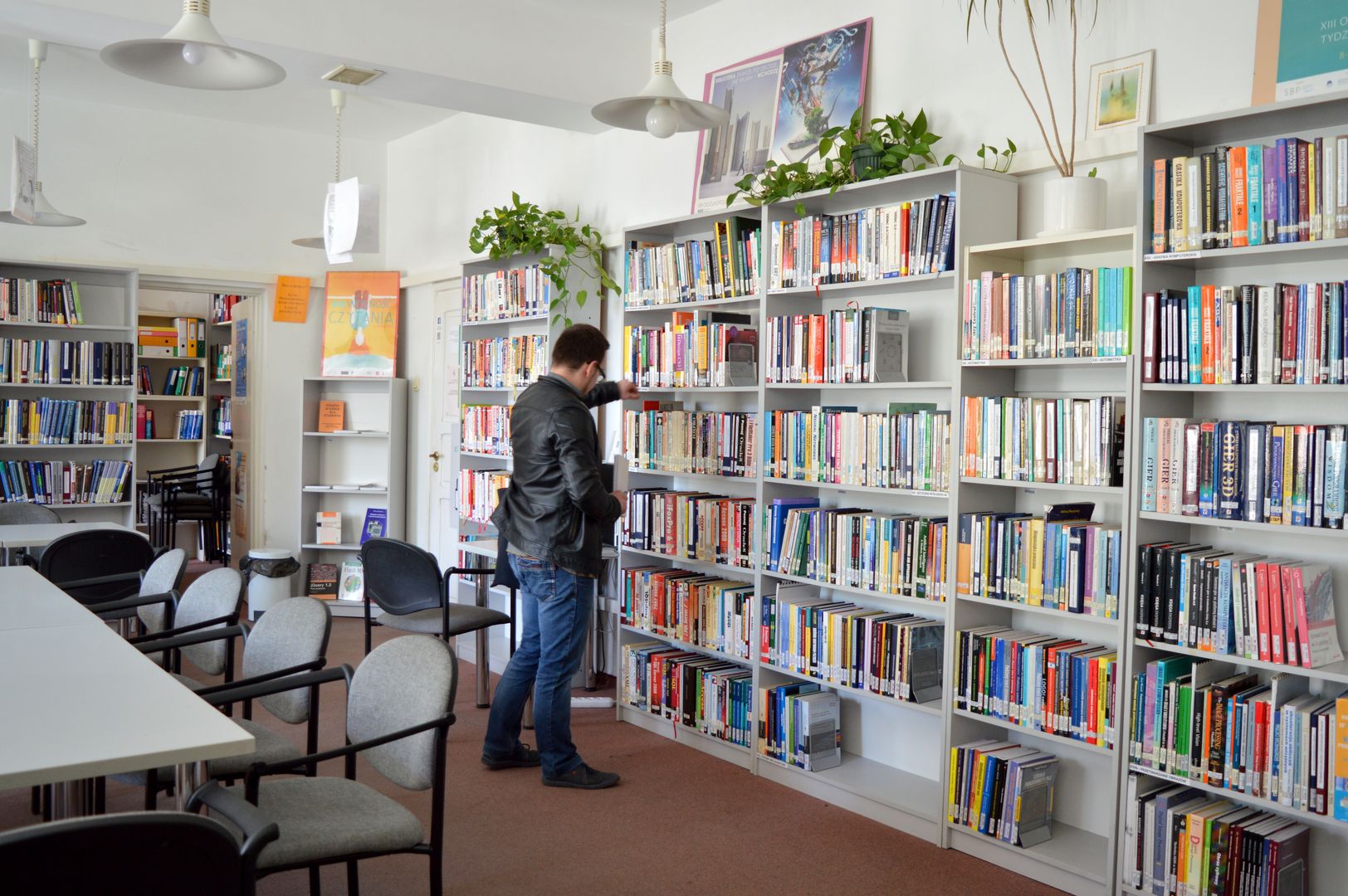 Czytelnik przed regałem z książkami w Bibliotece Wydziału Informatyki
